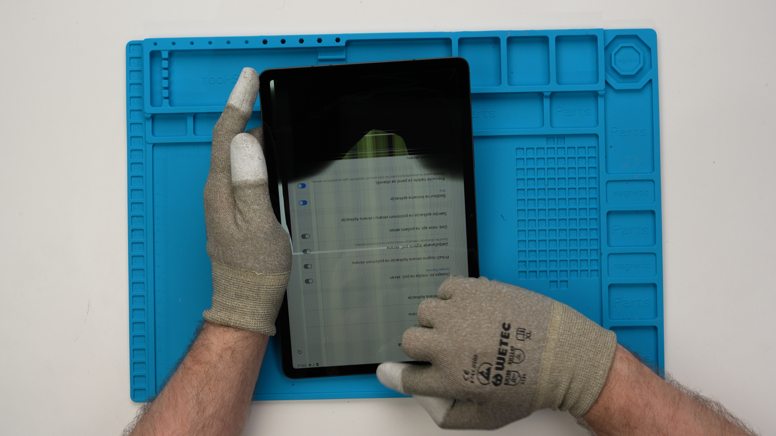 Ein Tablet mit internem Bildschirmbruch und Pixelfehlern wird zur Schadensanalyse von einem Experten gehalten.